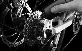 A person is working on a bicycle in black and white.