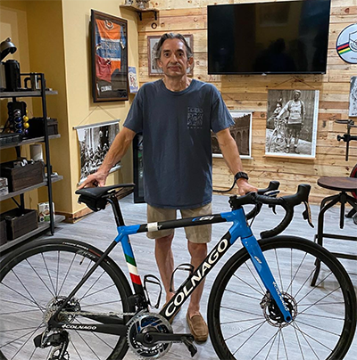A man standing next to a bike in a shop.
